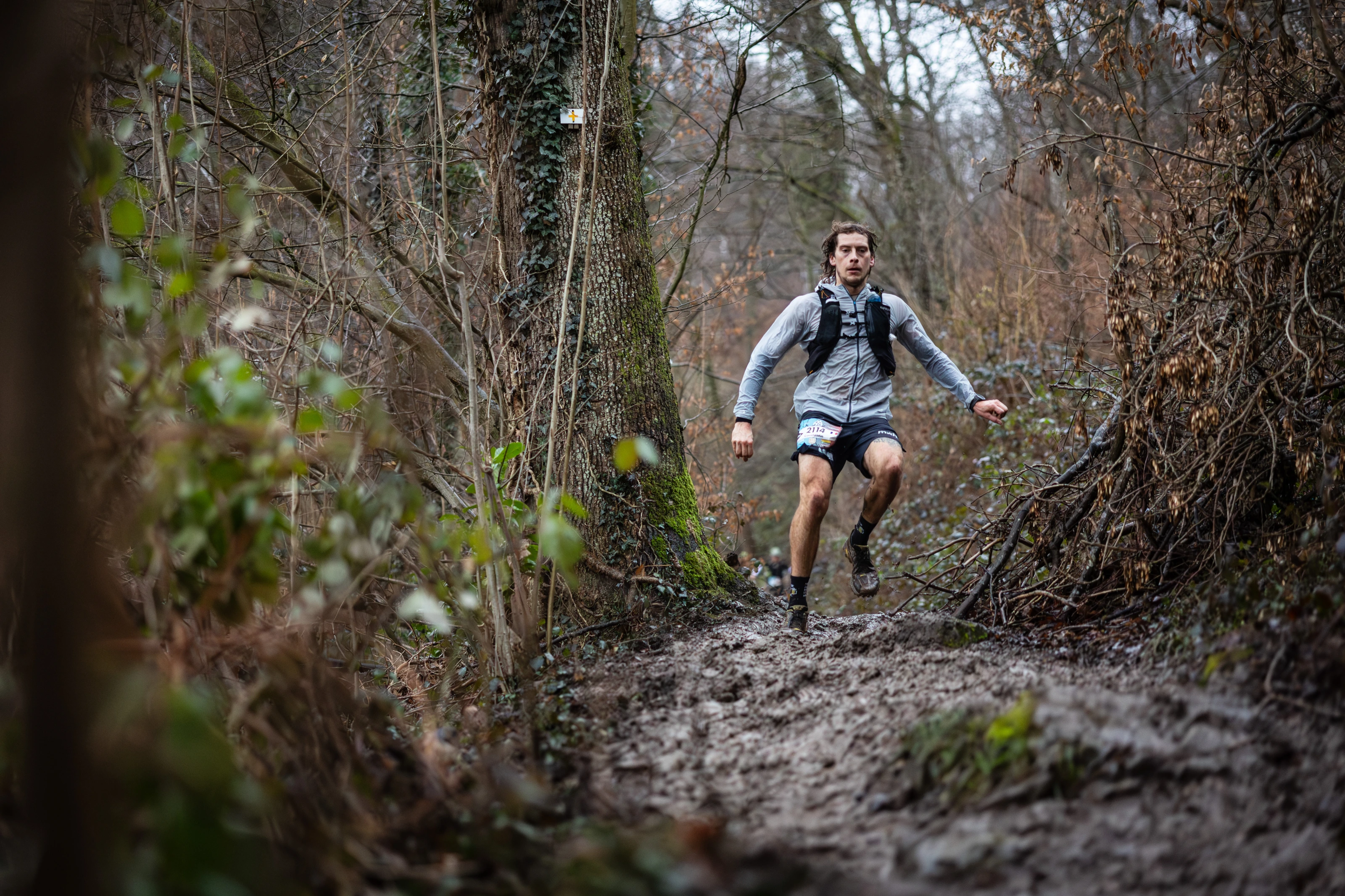 Des participants du Trail de la Sibérie dans une descente boueuse, le sourire aux lèvres.